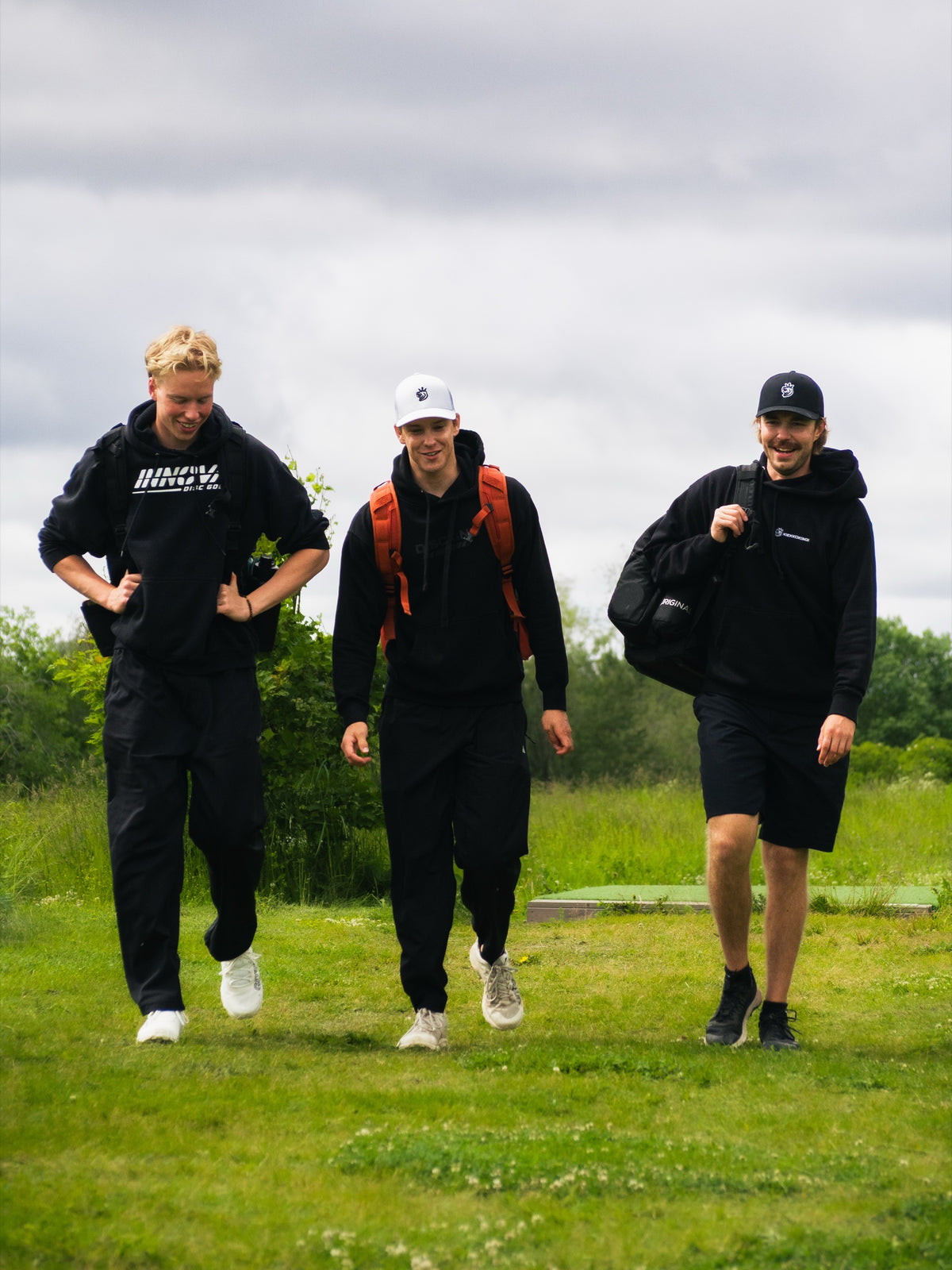 Tre spelare går på banan med väskor på ryggen