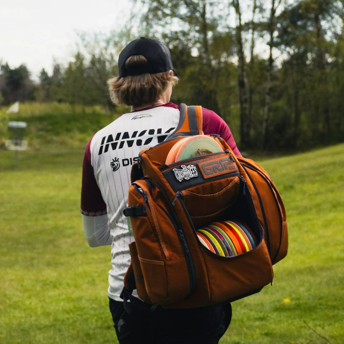 Väinö Mäkelä kävelee frisbeegolfradalla bägi selässä.